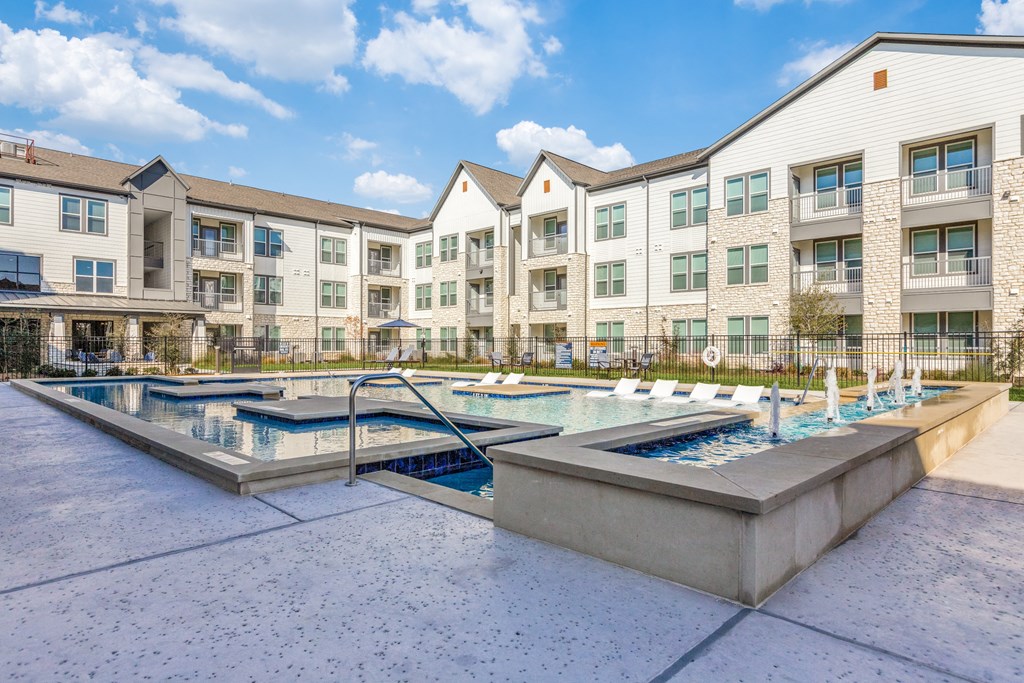 our apartments feature a community pool and spa with an apartment building in the background
