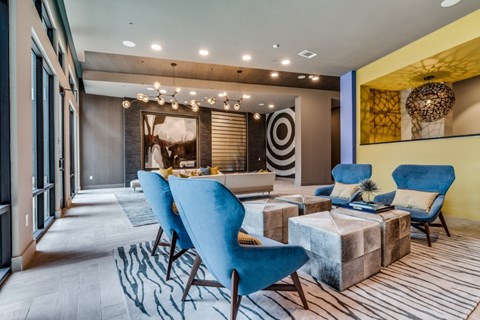 A modern living room with blue chairs and a patterned rug.