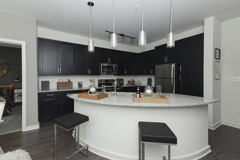 a kitchen with black cabinets and a white island with black stools