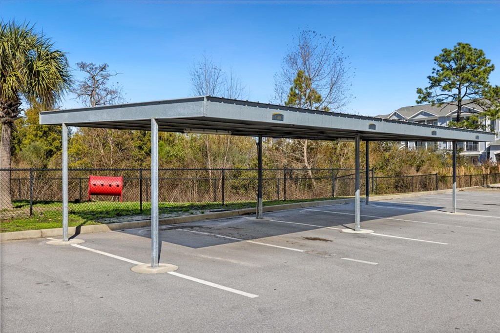 A parking lot with a grey canopy and a red object underneath.