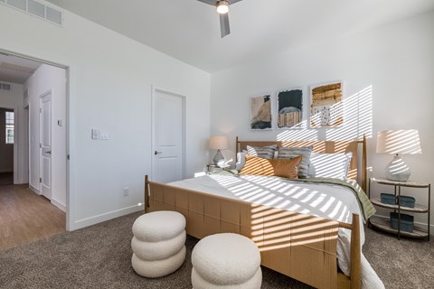 A bedroom with a bed, a ceiling fan, and a nightstand.