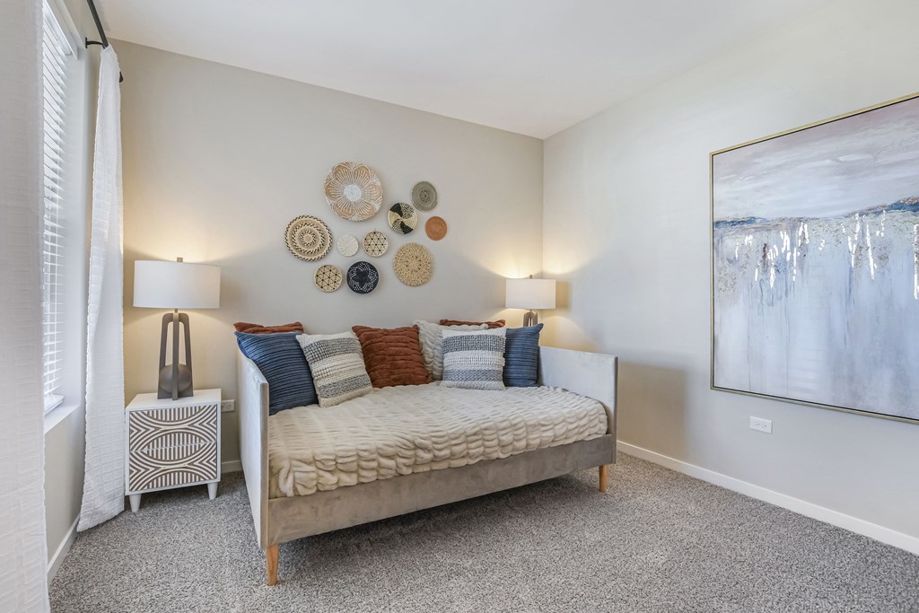 A bedroom with a bed, nightstand, and a painting on the wall.