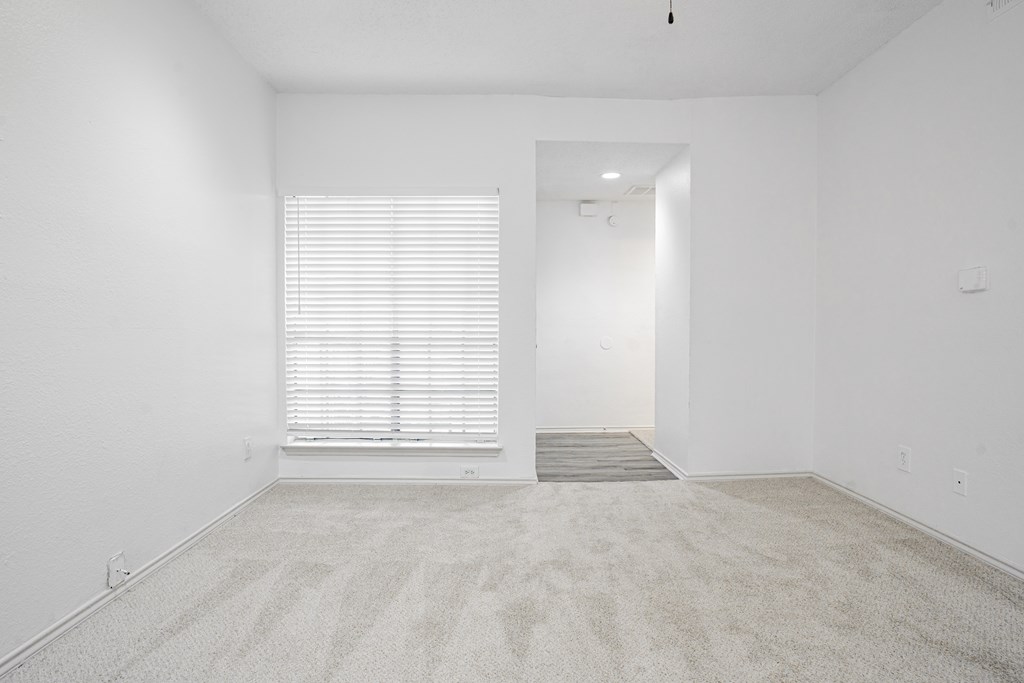an empty room with a window and white walls