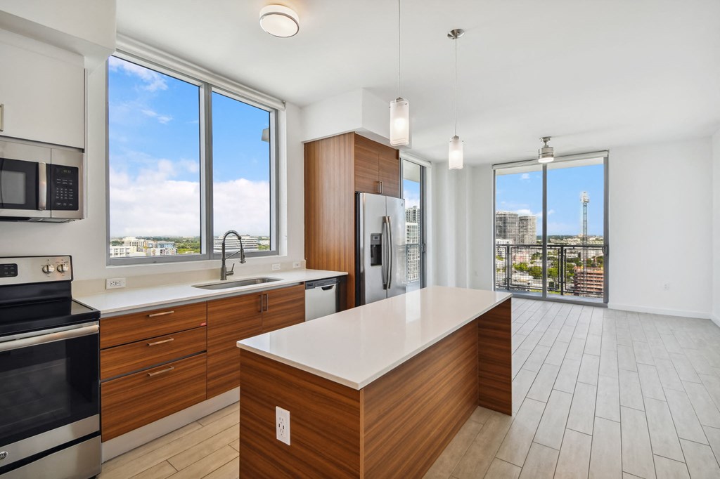 a kitchen with wooden cabinetry and a large center island with a white countertop