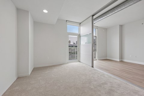 A spacious room with a sliding door leading to a balcony.