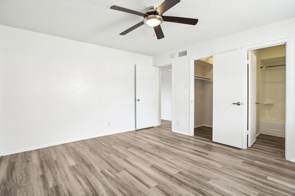 A room with a ceiling fan and wooden flooring.