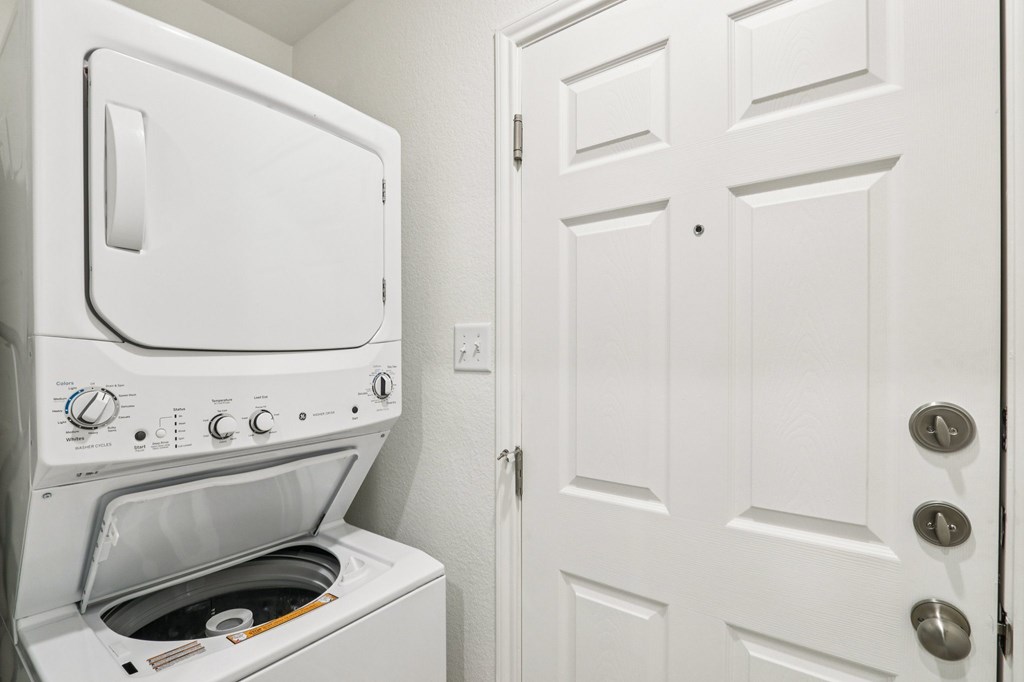 A white oven with a door open is in a room with a white door.