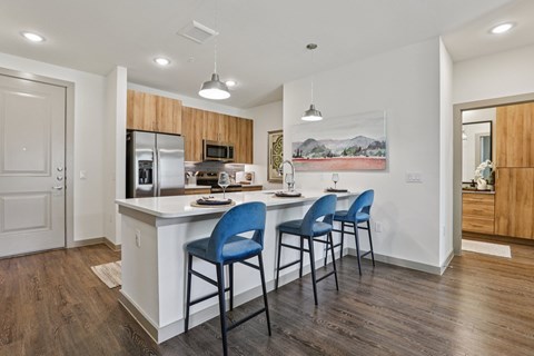 A kitchen with a white counter and blue chairs.