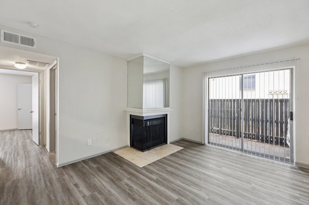 an empty living room with a fireplace and a door to a balcony