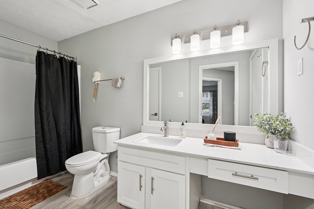 A white bathroom with a toilet, sink, and mirror.