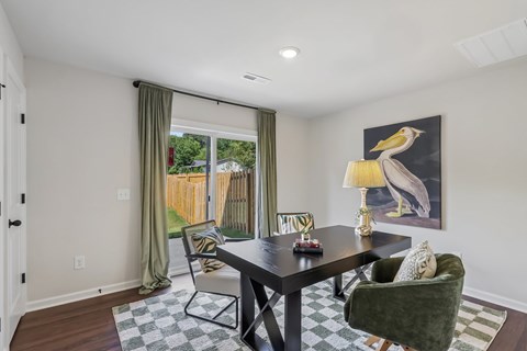 A dining room with a black table and green chairs.