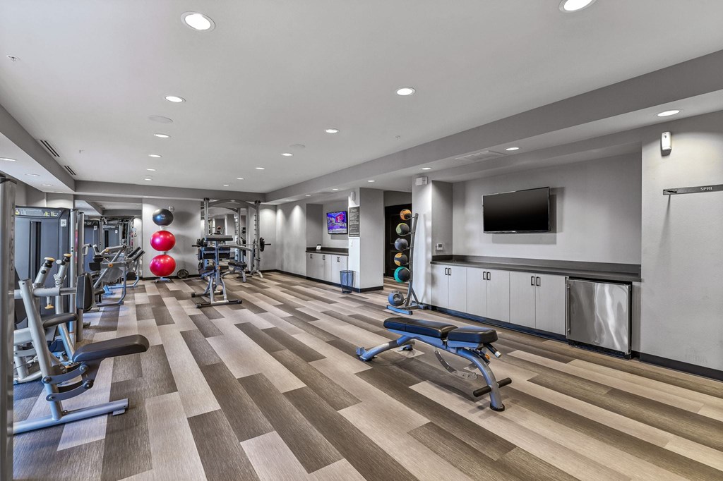 A gym with a variety of equipment including treadmills, weights, and exercise machines.