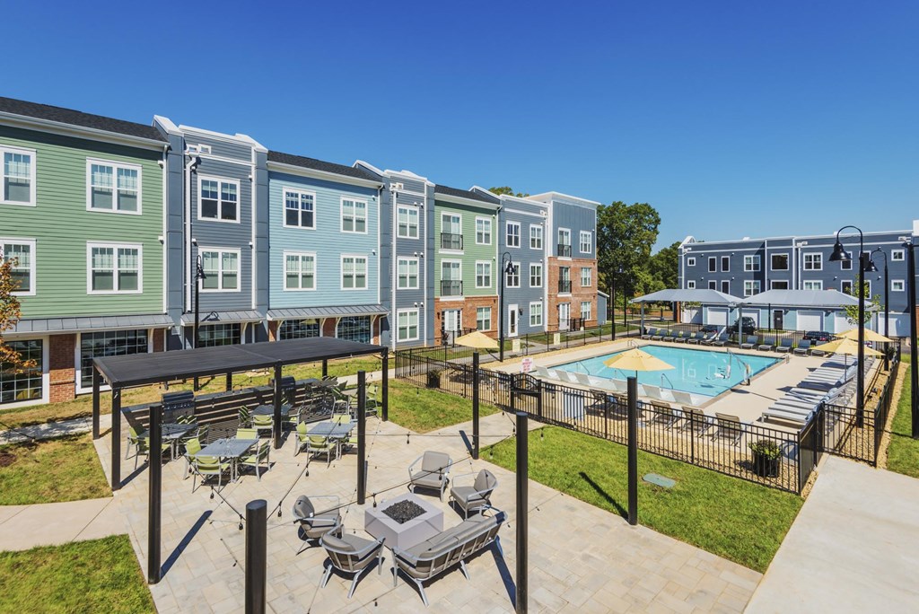 A pool area with a table and chairs is surrounded by apartment buildings.