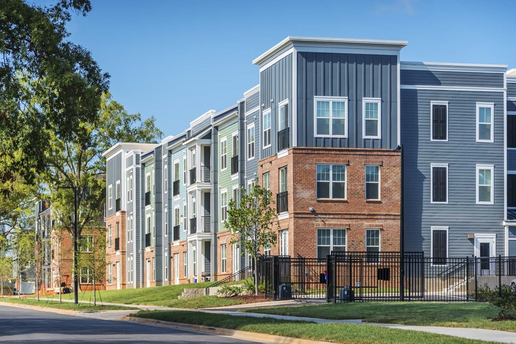 A row of modern townhouses with a black fence in front.