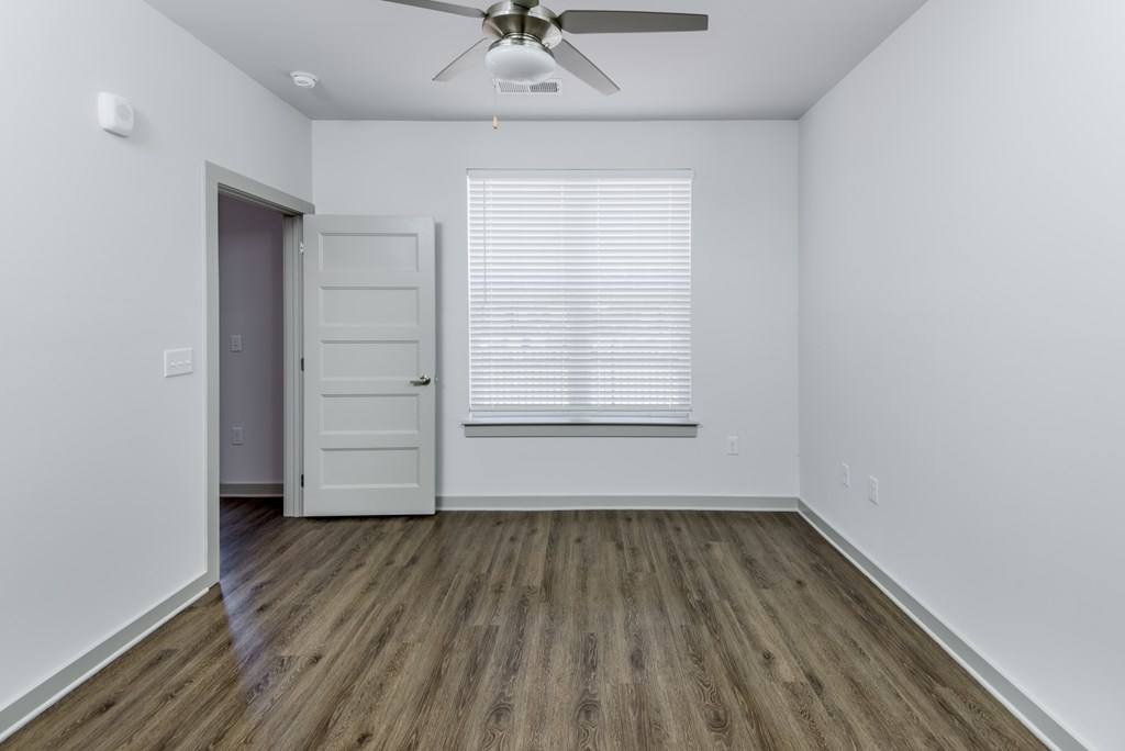 A room with a ceiling fan and a window with blinds.