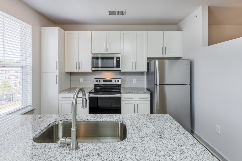 A kitchen with a granite countertop and stainless steel appliances.
