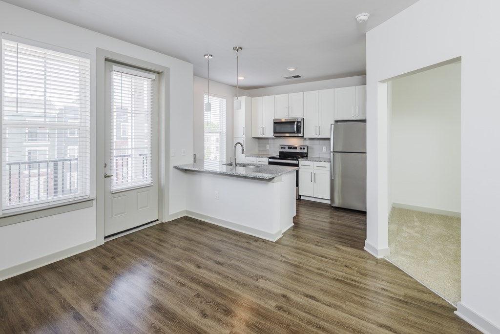 A kitchen with white cabinets and a wooden floor.