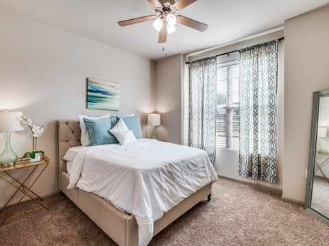 A bedroom with a large bed and a ceiling fan.