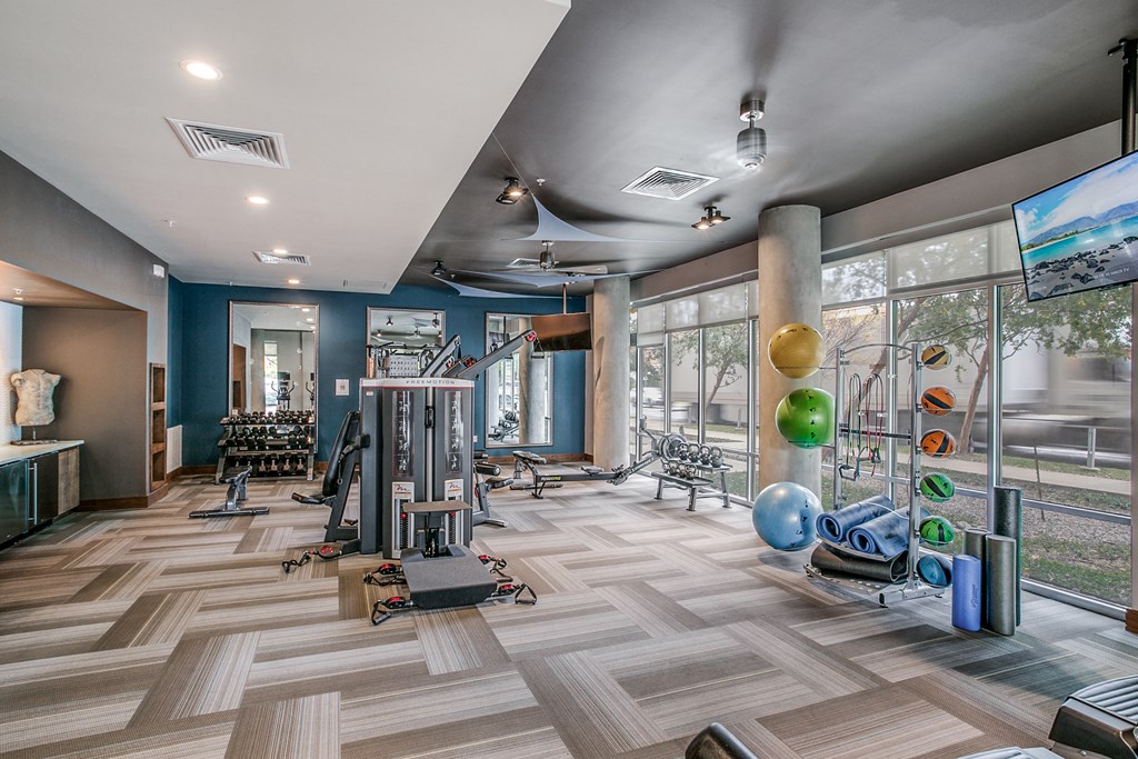 a gym with weights and other exercise equipment and large windows