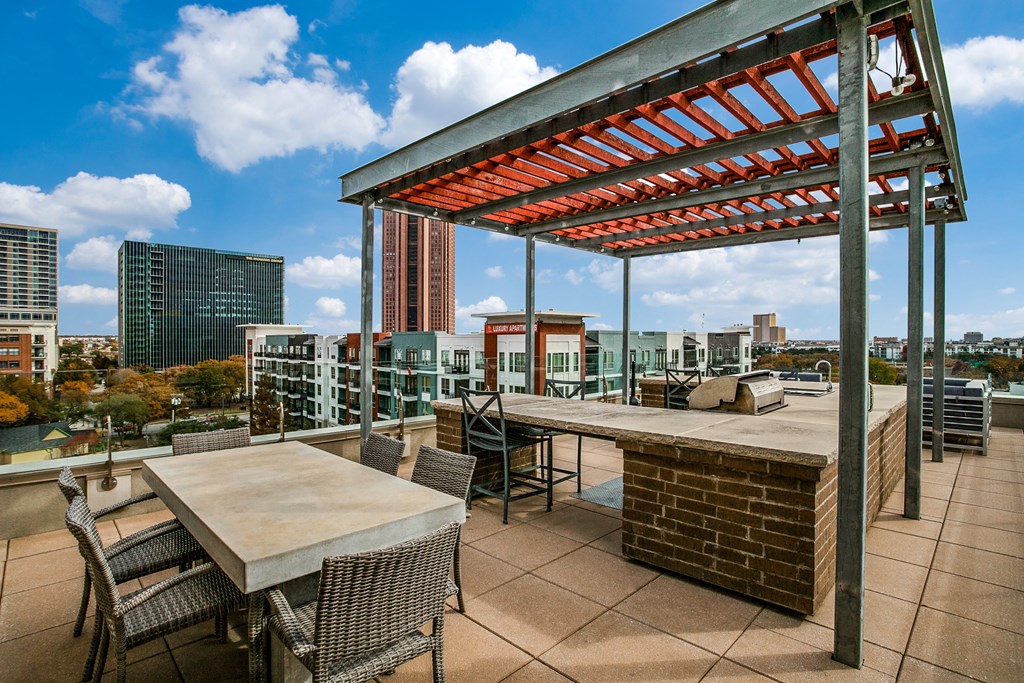 a rooftop deck with a bar and tables and a city in the background