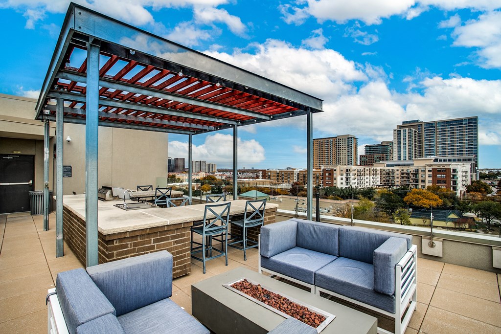 a rooftop patio with furniture and a city in the background