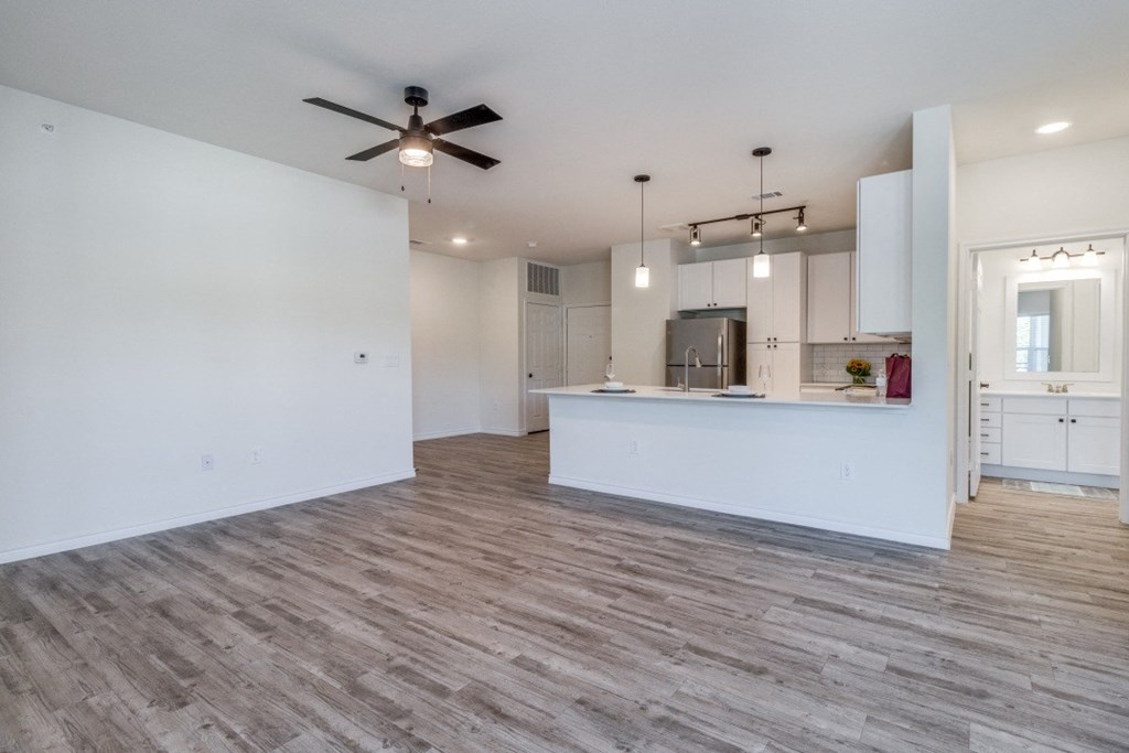an empty living room and kitchen with a ceiling fan