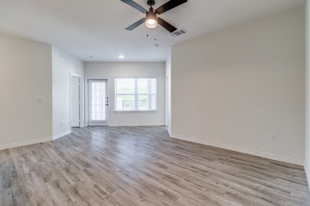 an empty living room with white walls and a ceiling fan