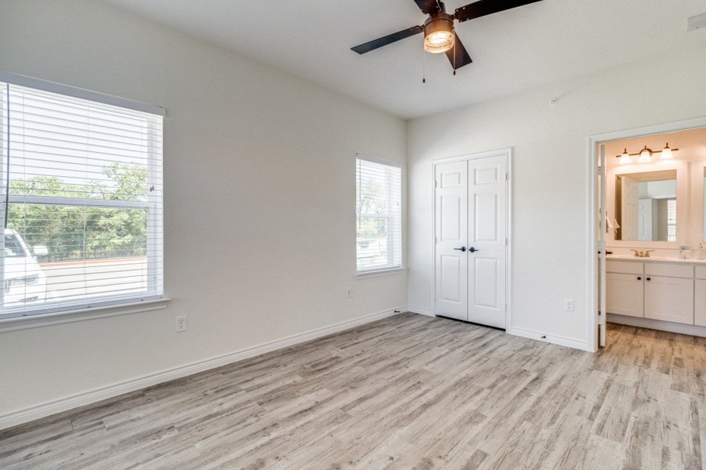 an empty living room with a ceiling fan and a window