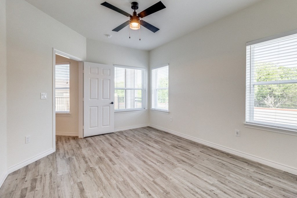 an empty living room with a ceiling fan and windows