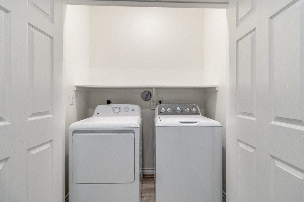 a washer and dryer in a laundry room with white walls and white doors
