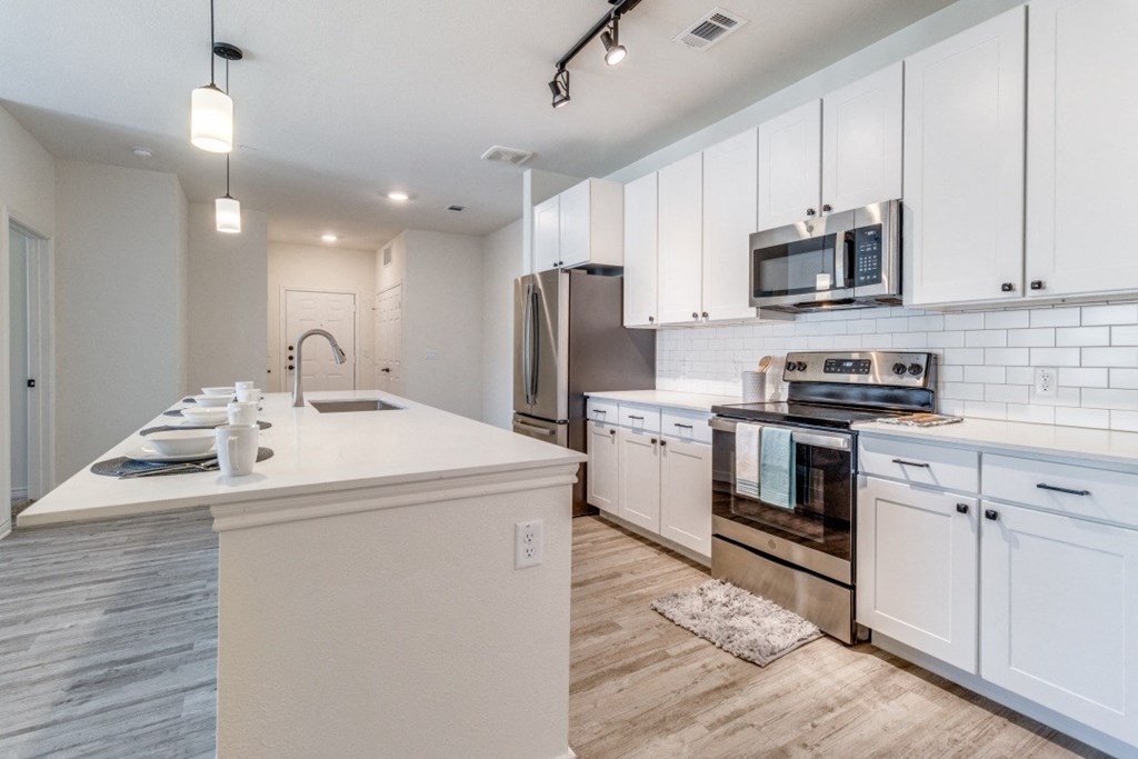 a kitchen with white cabinets and a counter top and a stove