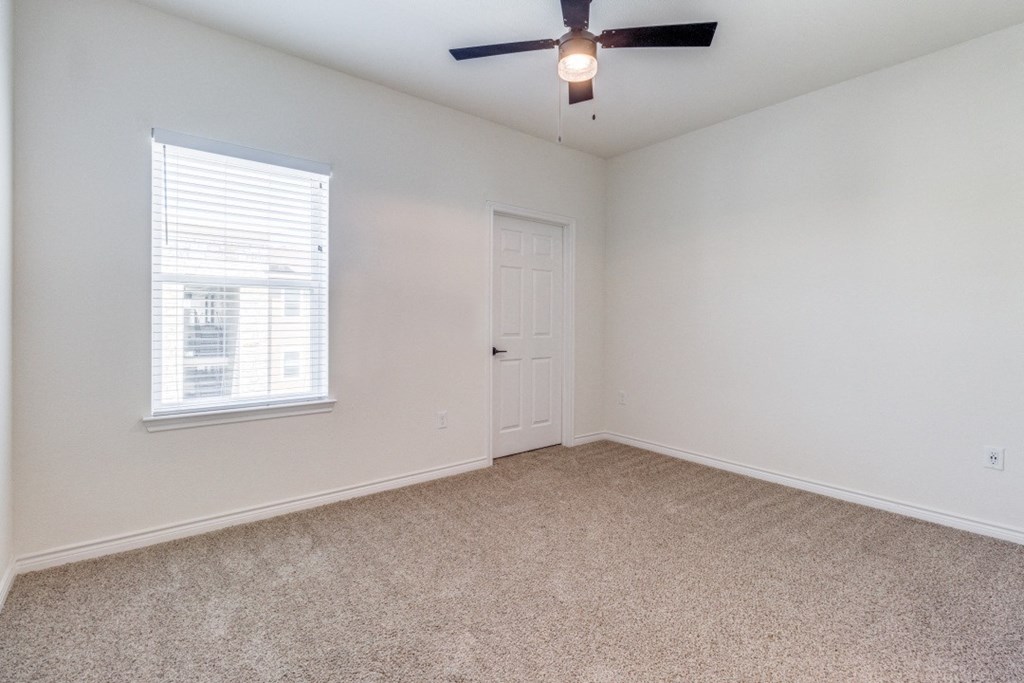 an empty living room with a ceiling fan and a window