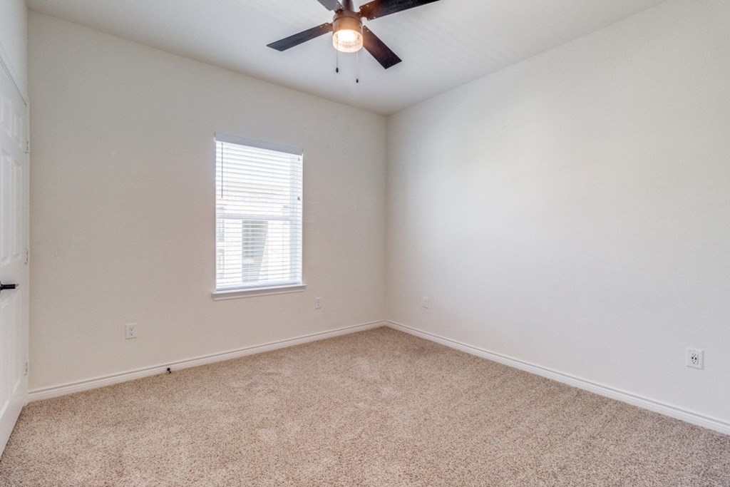 an empty room with a ceiling fan and a window