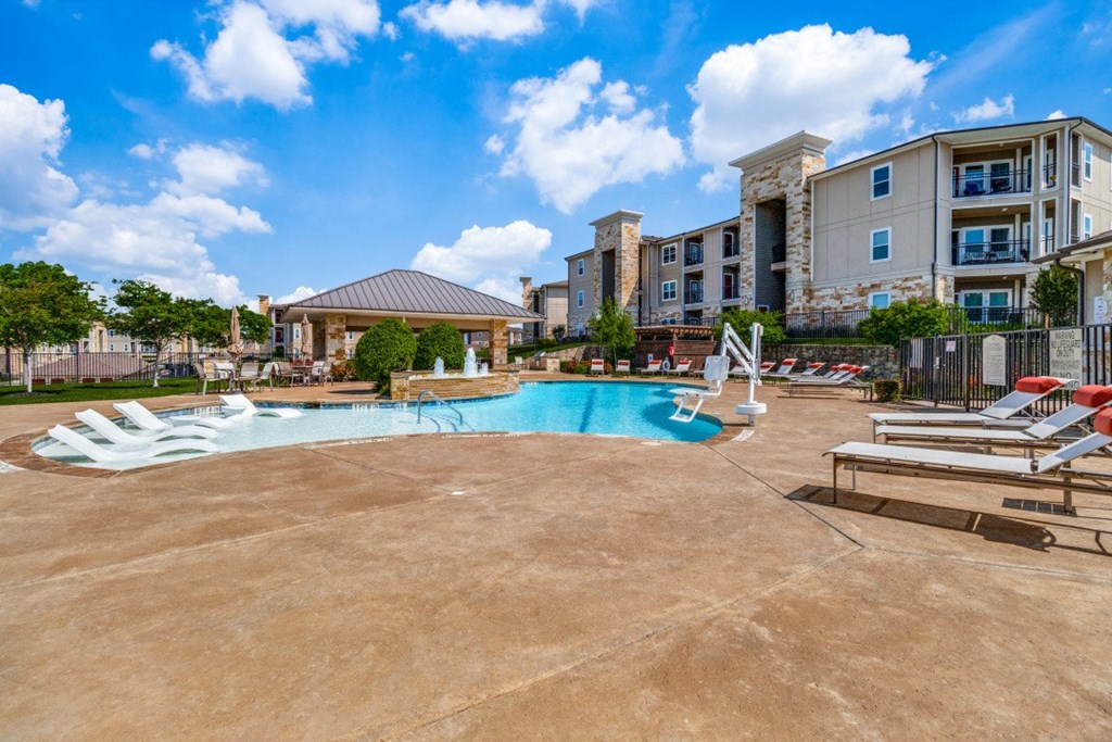 a resort style pool with lounge chairs and a building in the background