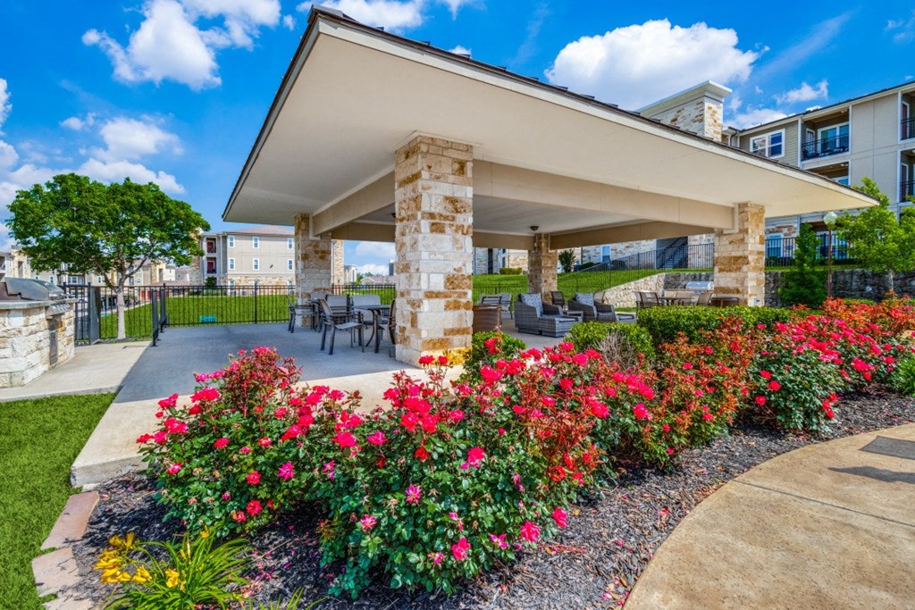 a patio with flowers and a table and chairs in front of a building