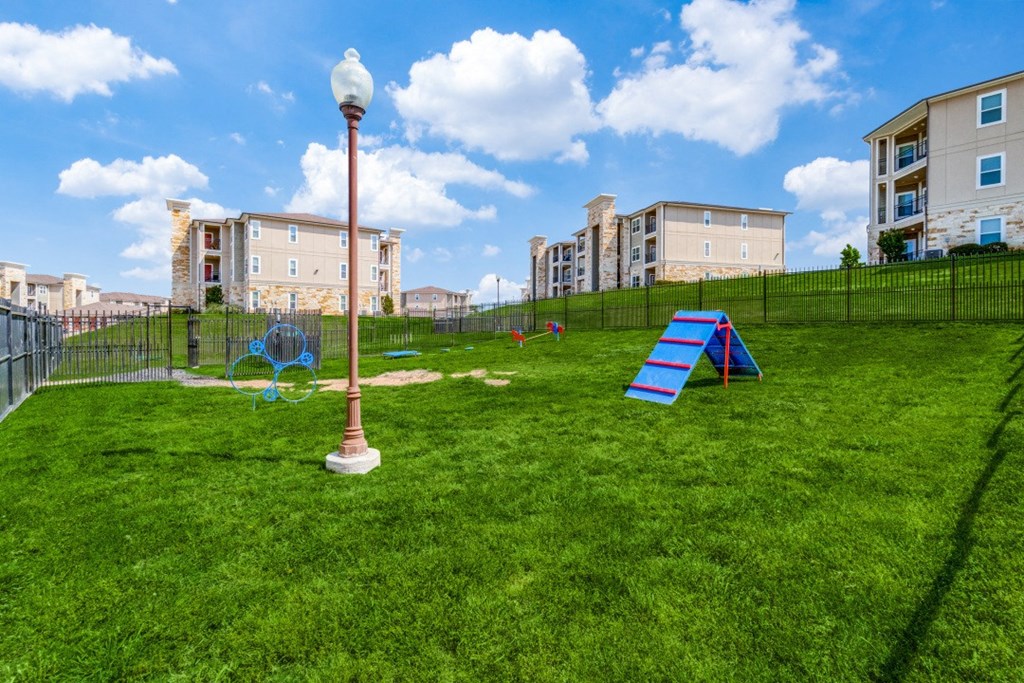 a playground on the grass with apartments in the background