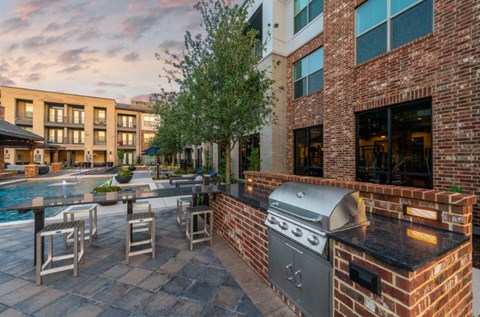 a patio with a grill and a pool in front of a building
