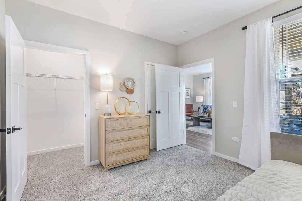A bedroom with a large bed and a wooden chest of drawers.