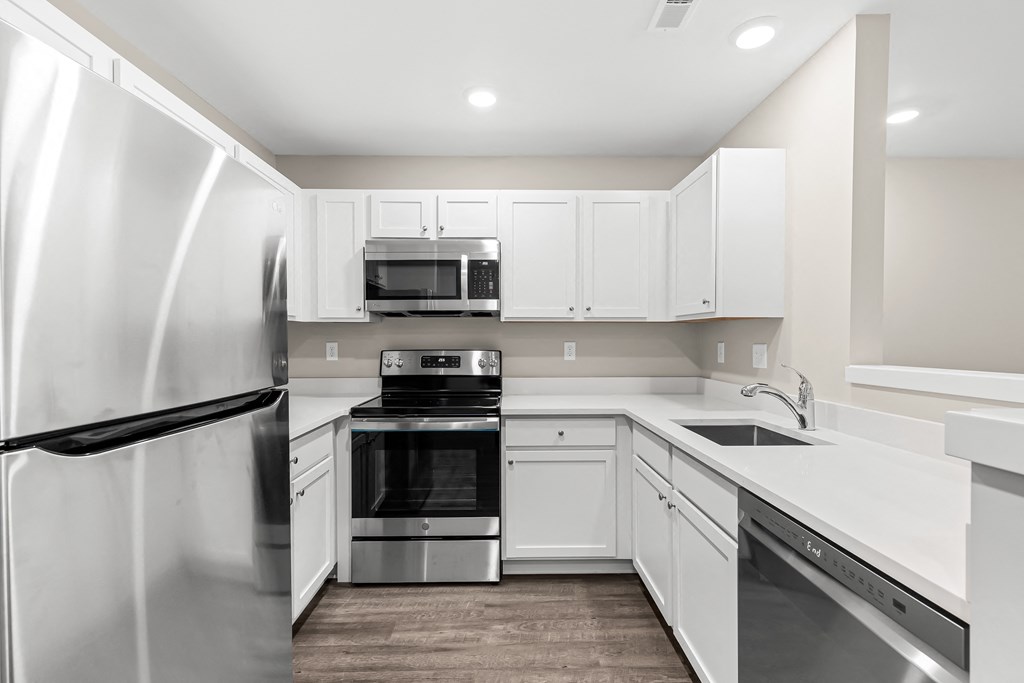 a white kitchen with stainless steel appliances and white cabinets