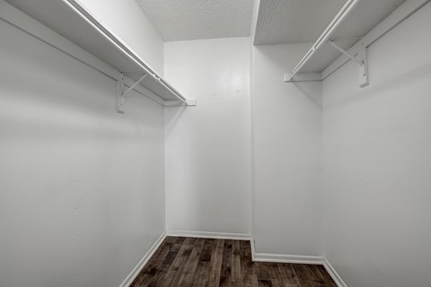 the living room of an apartment with white walls and wood flooring