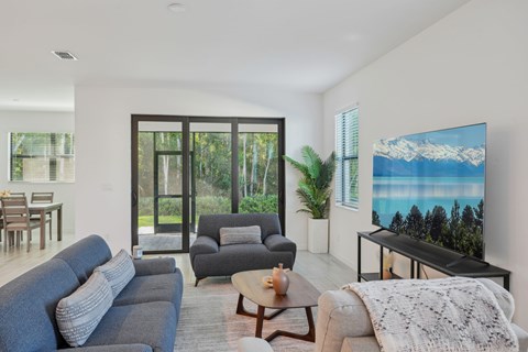 A living room with a grey sofa and a large painting of a mountain landscape on the wall.