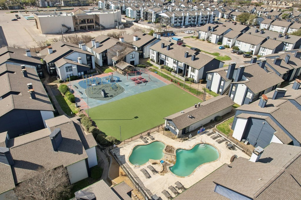 A bird's eye view of a neighborhood with a large swimming pool in the foreground.
