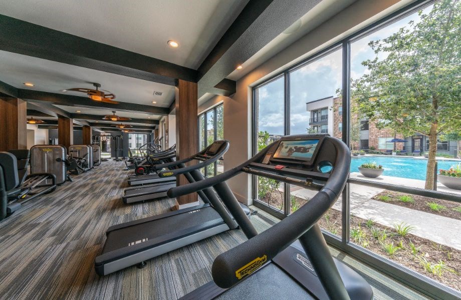 the gym is equipped with cardio equipment and views of the pool