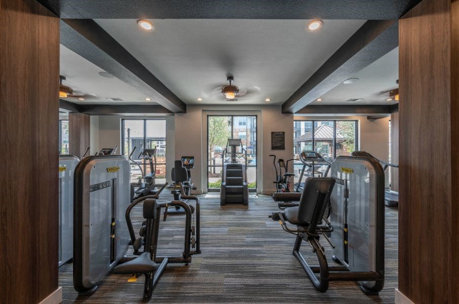 a gym with weights and cardio equipment on the floor and windows