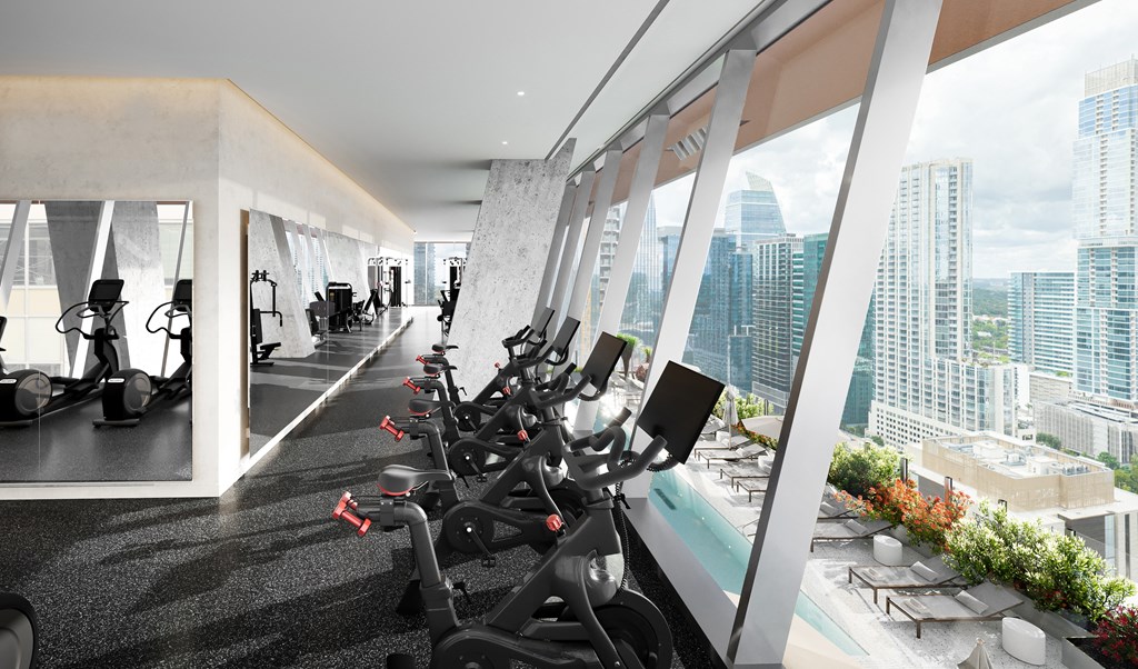 a row of workout bikes in a gym with a view of the city