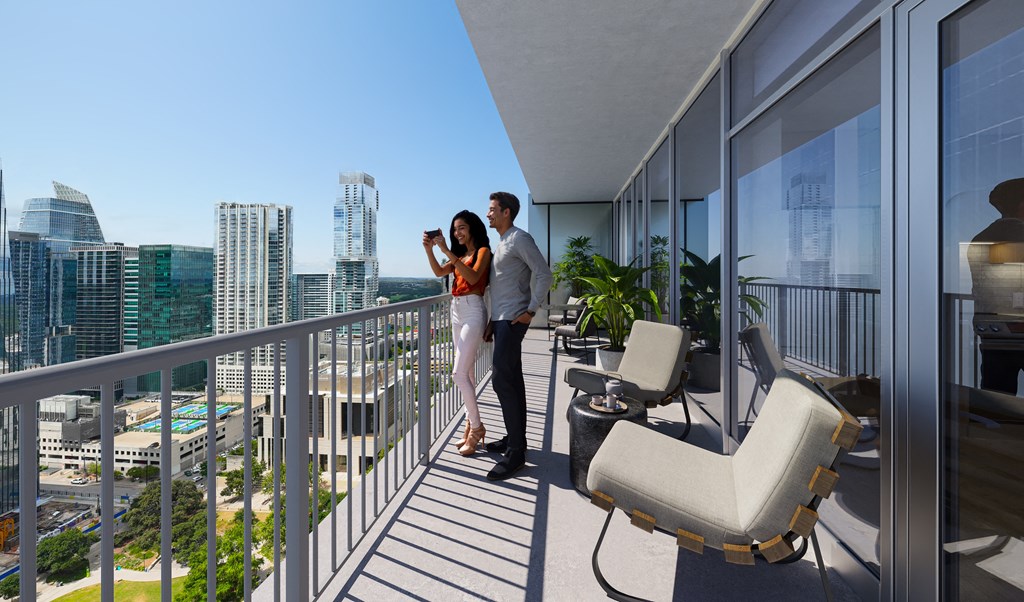 a man and woman standing on a balcony overlooking the city