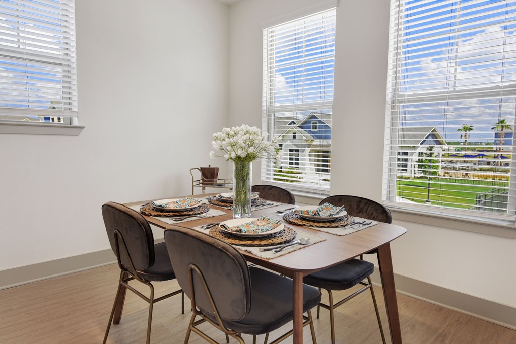 a dining room with a table and chairs and two windows
