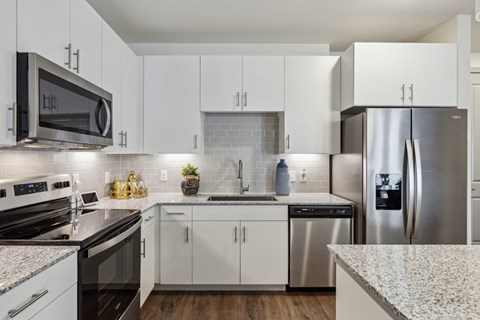 A modern kitchen with white cabinets and stainless steel appliances.