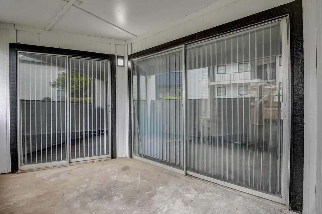 a patio with two sliding glass doors and a tree in the background