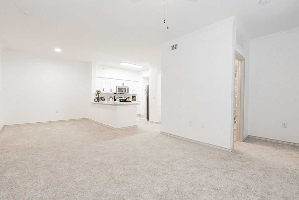 an empty living room and kitchen with white walls and flooring
